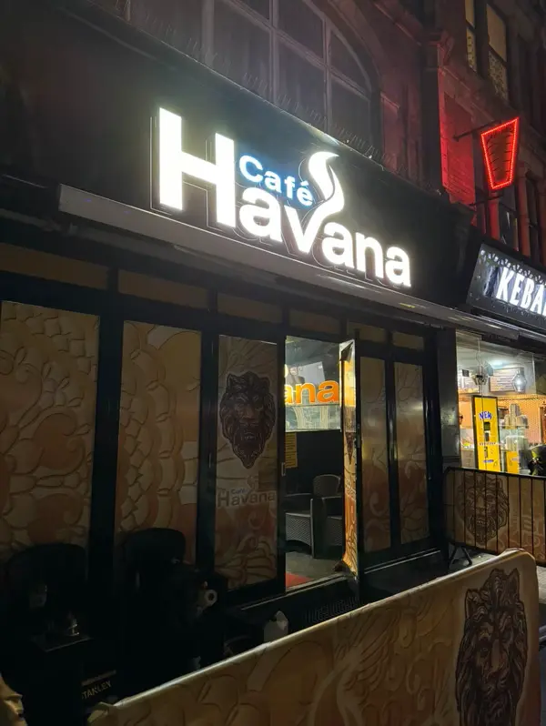 Face-lit 3D sign for Café Havana with bold white lettering and a stylized steam swirl in the logo on a black storefront.
